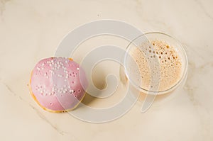 donut in violet glaze and a cappuccino glass /donut in violet glaze and a cappuccino glass on a white background, top view