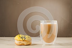 donut in yellow glaze and a cappuccino glass/donut in yellow glaze and a cappuccino glass on a brown background
