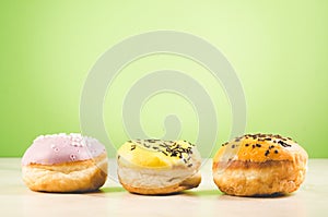 Donuts. Assorted donuts lying on a white table on green background. Ð¡oncept sweet food