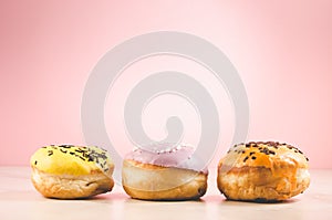 Donuts. Assorted donuts lying on a white table on pink background. Ð¡oncept sweet food