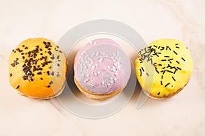 Donuts. Assorted donuts lying on a white table on purple background, top view. Ð¡oncept sweet food