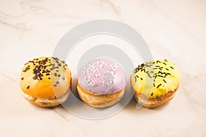 Donuts. Assorted donuts lying on a white table on purple background, top view. Ð¡oncept sweet food