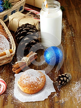 Donuts berliner and a glass of milk surrounded by Christmas attributes