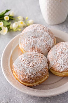donuts berliners with filling sprinkled with powdered sugar on a white plate photo