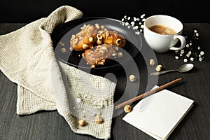donuts with caramel and hazelnuts, cup of coffee on the rustic table