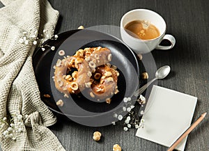 donuts with caramel and hazelnuts, cup of coffee on the rustic table