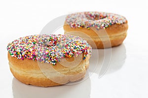 Donuts with colorful sprinkles on white background with copy space