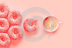 Donuts and cup of coffee in color of panton living coral, pink background