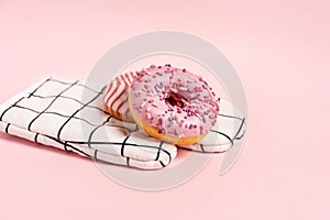 Donuts decorated with icing and topping lie on the chef`s glove on a pink background top view copy