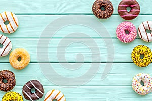 Donuts of different flavors for breakfast on mint green wooden background top view space for text