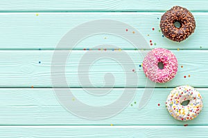 Donuts of different flavors for breakfast on mint green wooden background top view space for text