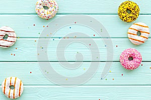 Donuts of different flavors for breakfast on mint green wooden background top view space for text