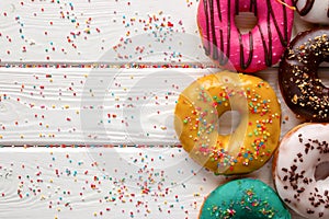 Donuts in different glazes on wooden background and space for text