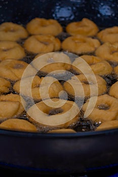 Donuts fritter making machine, handmade, frying sweet and tasty donuts in hot oil in a pan photo