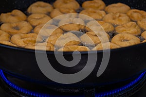 Donuts fritter making machine, handmade, frying sweet and tasty donuts in hot oil in a pan photo