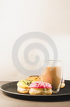 donuts in glazes and a glass of a cappuccino /donuts in glazes and a glass of a cappuccino on a black tray on a white background