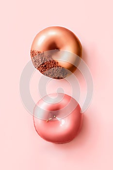 Donuts with icing and chocolate on pastel pink background. Sweet donuts