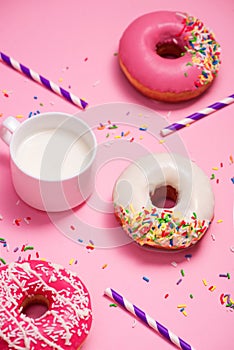 Donuts with icing and milk on pastel pink background. Sweet donuts.