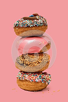 Donuts one on each other with icing and chocolate on pink background. Sweet donuts