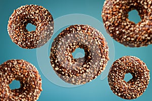 donuts with peanuts flying over blue background, junk food concept