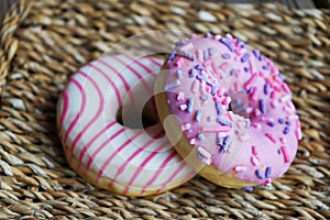 Donuts with pink icing and sprinkles on a wicker napkin