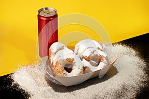 Donuts sprinkled with powdered sugar on a paper plate. Takeout food. Colored background