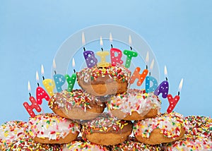 Donuts stacked with happy birthday candles, blue background