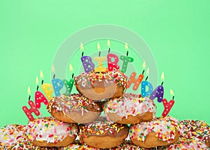 Donuts stacked with happy birthday candles, green background