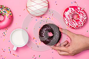 Donuts, sweetmeats candy on pink background. Hand holds donut photo