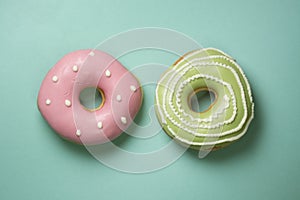 Donuts on turquose background with green, pink icing and white sugar decorations