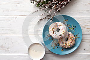 Donuts on a white wooden background with a cup of milk and willow twigs