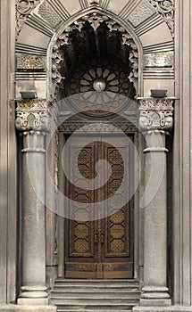 The door of ancient building with columns and rose window above it.