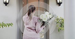 Door, flowers and romantic surprise with a woman giving a floral gift at a front door in celebration of an event. Knock