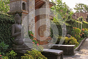 Door or gate to enter into traditional balinese garden lanscaping and budha statues