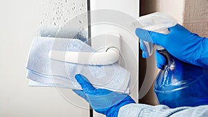 Door handle cleaning by antibacterial alcohol spray. Woman Houseworker in rubber blue gloves clean Door knob by cloth rag. New