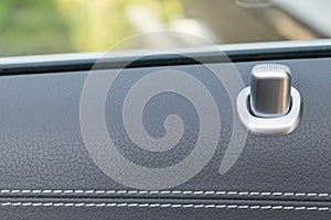 Door handle with lock control buttons of a luxury passenger car. Black leather interior of the luxury modern car. Modern car