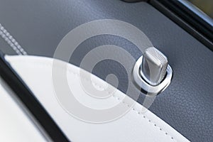 Door handle with lock control buttons of a luxury passenger car. Black leather interior of the luxury modern car. Modern car