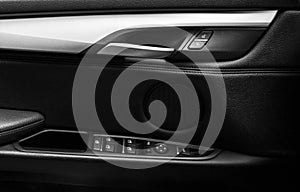 Door handle with Power window control buttons of a luxury passenger car. Black leather interior of the luxury modern car. Modern c