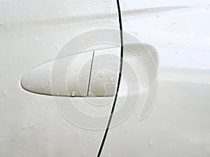 Door handle of a white car with drops of rain photo