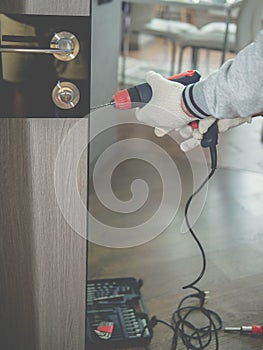 A door installer at work  a carpenter drilling a door lock  a handyman repairing an interior door. Home worker.