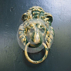 A door knocker is a fixture on the front door of a house. It is made of metal and has the form of a ring, which is