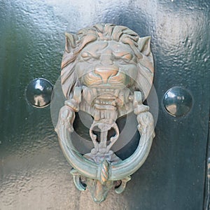 A door knocker is a fixture on the front door of a house. It is made of metal and has the form of a ring, which is