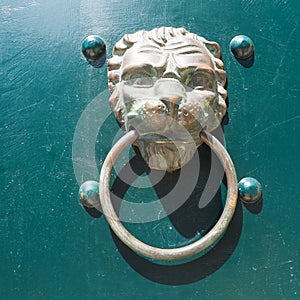 A door knocker is a fixture on the front door of a house. It is made of metal and has the form of a ring, which is