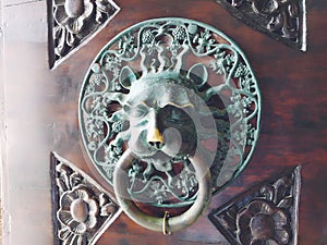 A door knocker is a fixture on the front door of a house. It is made of metal and has the form of a ring, which is