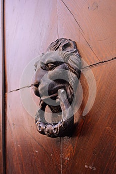 Door knocker in the form of a head on a wooden door