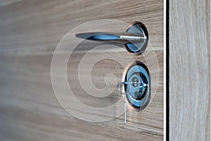 Door lock with key and handle close up, beautiful modern wooden entrance door to the apartment