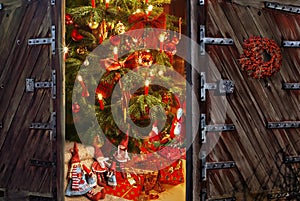 Door opening into a room with christmas tree and gift