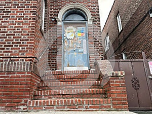 Door of a red brick building with multiple caution signs