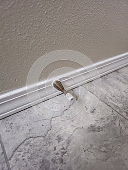 Door stop attached to trim on wall