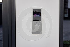 Doorbell with video camera and microphone, on the white wall of an apartment building, doorbell camera